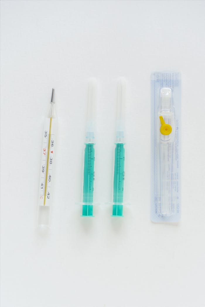 Minimalist photo of syringes and thermometer against a white background.