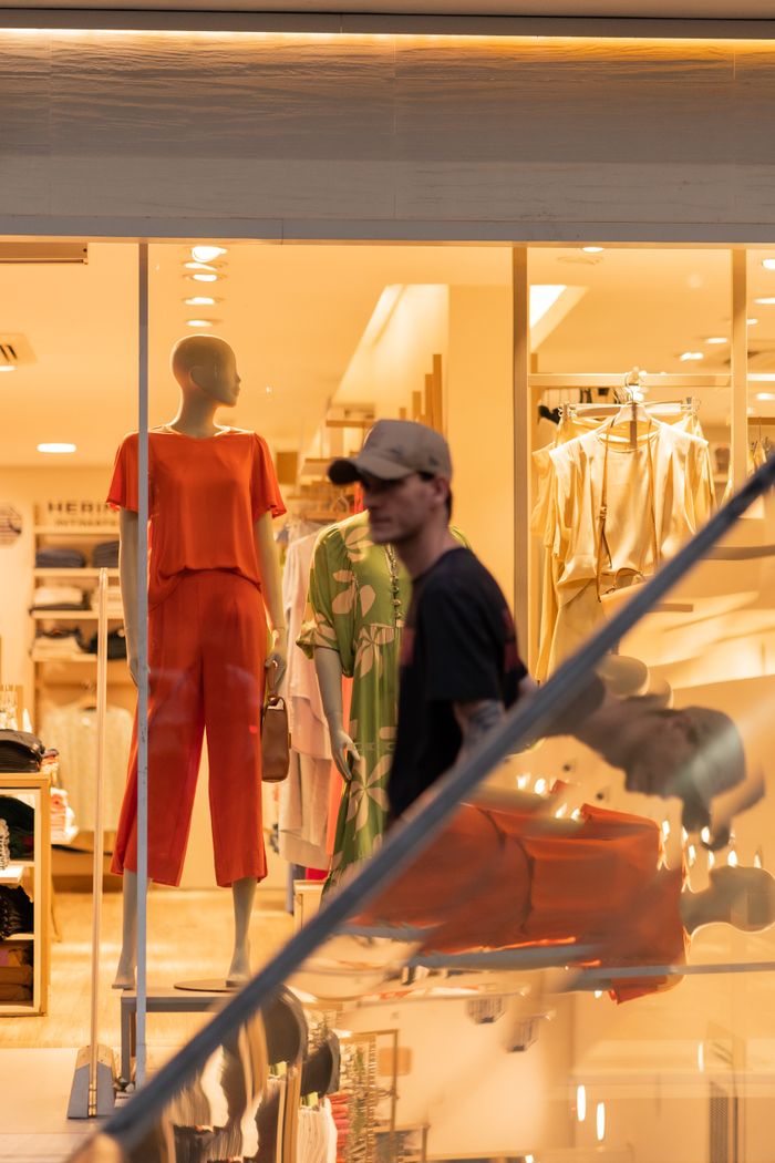 services-01 Man walking past stylish clothing store display at a shopping mall.