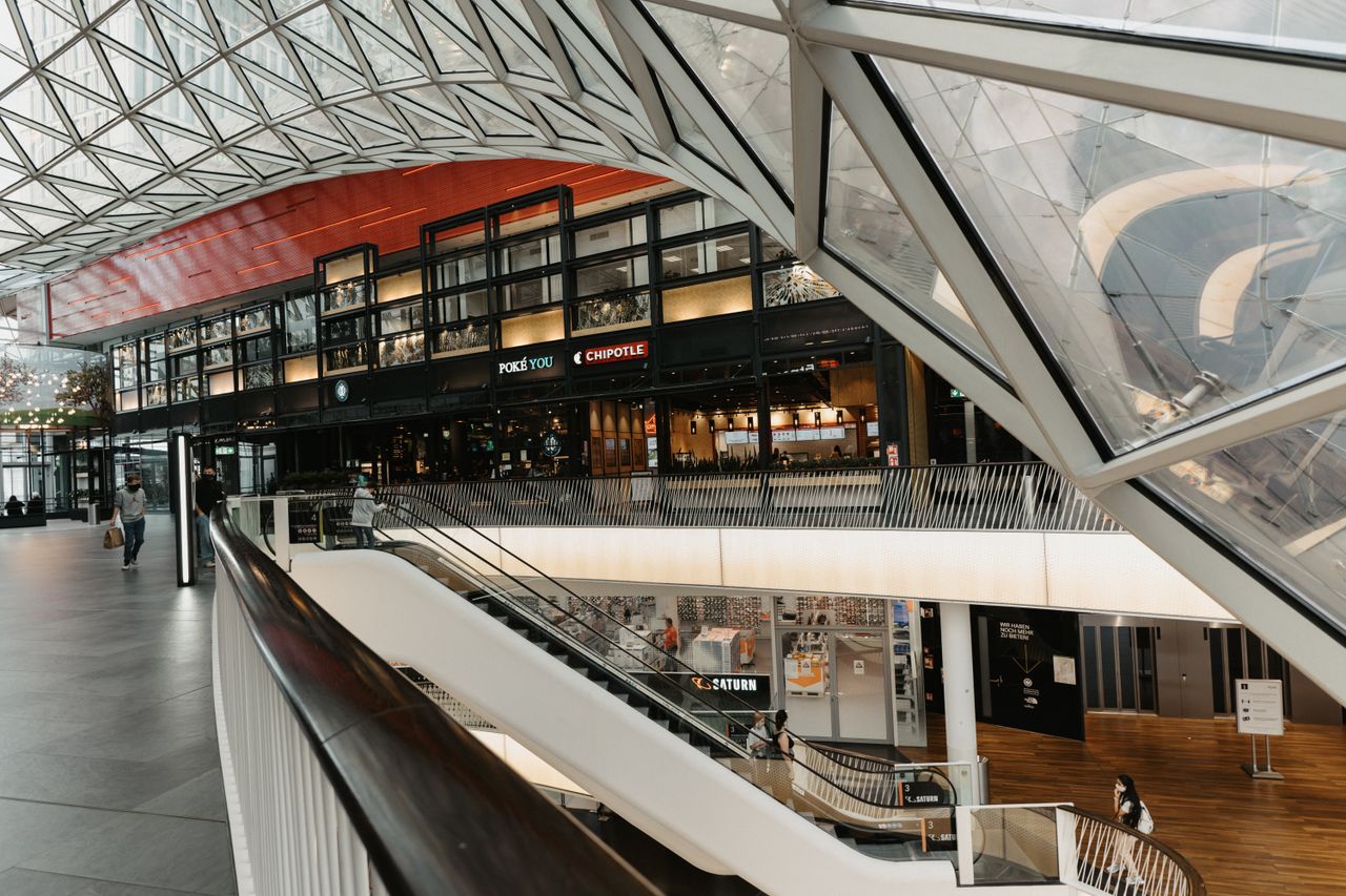 services-img Interior view of a modern shopping mall featuring a striking glass ceiling and multiple floors.