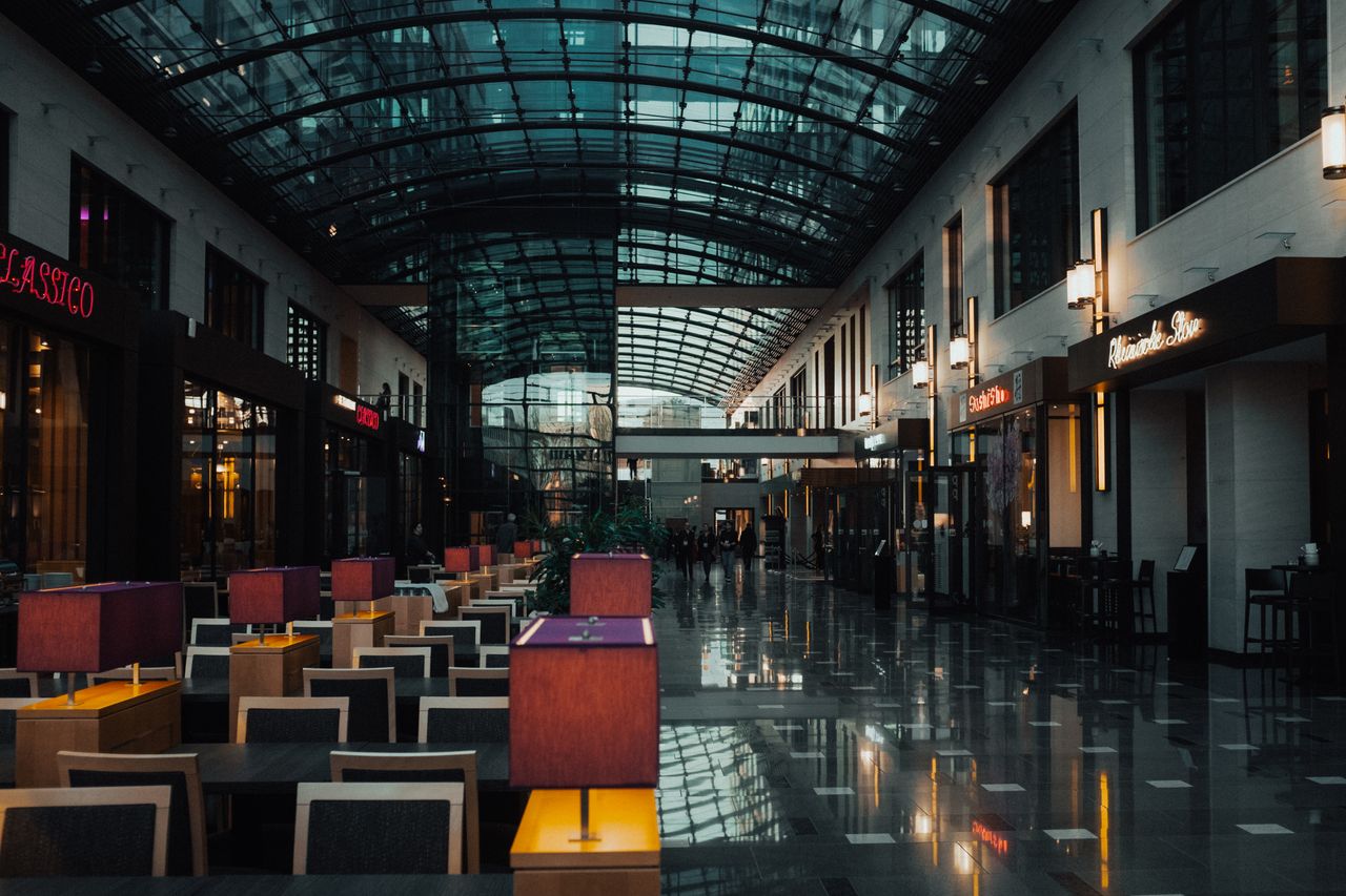 why-choose-us Elegant indoor view of a modern shopping mall with a glass ceiling and stylish lighting.
